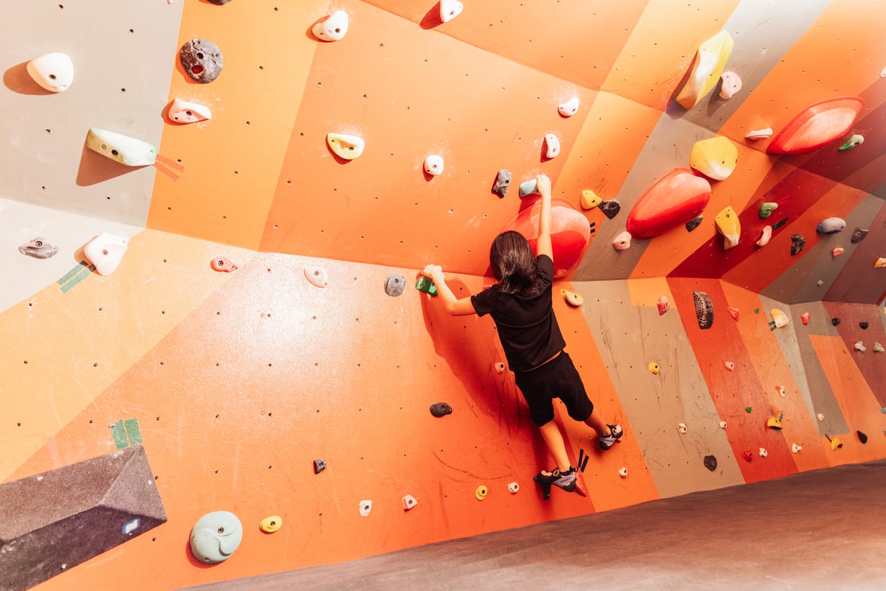 A boulderer traverses Climb Anytime's orange bouldering wall