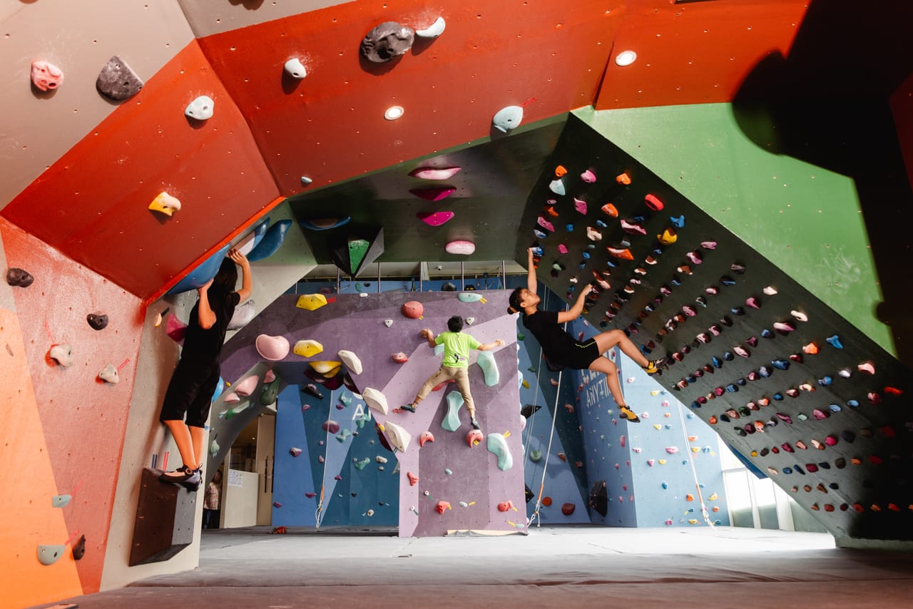 Kids and adults climb side by side across Climb Anytime's colorful bouldering walls