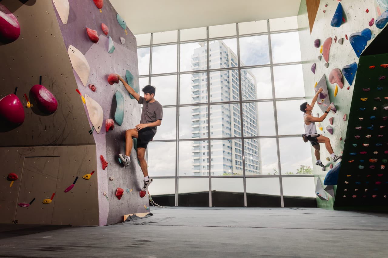 Climbers on Climb Anytime's tall walls in front of floor-to-ceiling windows overlooking Cagayan de Oro